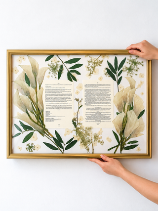 Pressed wedding bouquet arranged around the couple’s wedding vows in a gold 18x24 frame, combining preserved cream flowers and greenery into custom floral artwork by Forgiven Flower.