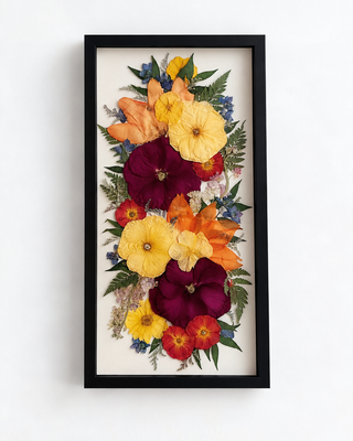Pressed funeral flower arrangement featuring yellow, orange, burgundy, and blue flowers with greenery, arranged vertically in a black frame by Forgiven Flower.