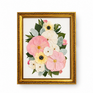 Custom pressed wedding bouquet featuring blush pink, ivory, and pale yellow flowers with green foliage in an ornate vintage gold frame by Forgiven Flower.