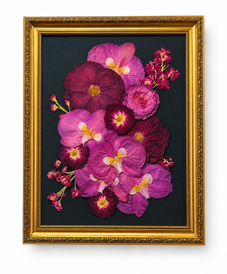 Custom pressed wedding bouquet featuring magenta, fuchsia, and plum flowers with delicate pink accents, displayed on a dark background in an ornate vintage gold frame by Forgiven Flower.